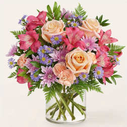 Mixed bouquet of pink and peach flowers in a clear glass vase