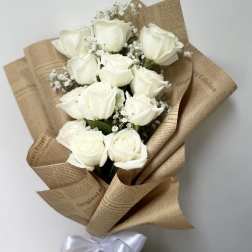 Bouquet of white roses wrapped in brown paper with a white ribbon