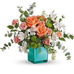 Peach roses and pink carnations in a turquoise glass vase