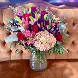 Bouquet of red roses, pink lilies, and hydrangea in a glass vase