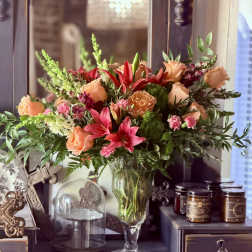Mixed bouquet of peach roses and pink lilies in a clear glass vase