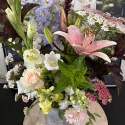 Mixed bouquet with pink lily, roses, and pale blue flowers in a vase