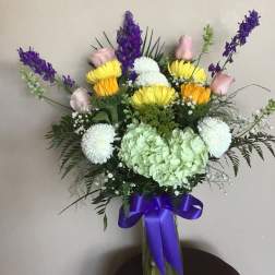Mixed bouquet in a glass vase with purple ribbon