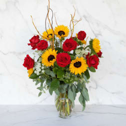 Bouquet of red roses and yellow sunflowers in a glass vase
