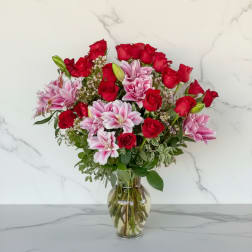 Bouquet of red roses and pink lilies in a clear glass vase