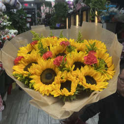 Bouquet of yellow sunflowers with pink carnations wrapped in brown paper