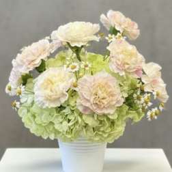 Pastel flower arrangement in a white pot with pale pink blooms and green hydrangeas