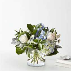 White roses and blue hydrangeas in a clear glass vase