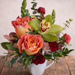 Mixed bouquet in a white mug with peach roses and green orchids