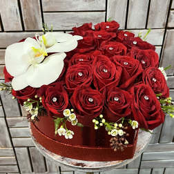 Red rose arrangement with a white orchid accent in a red hat box
