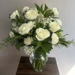 White roses and carnations arranged in a clear glass vase