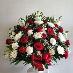 Red roses and white daisies in a white vase with a red ribbon