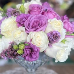Purple and white roses arranged in a glass vase