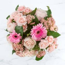 Pink roses and gerbera daisies arranged in a round bouquet