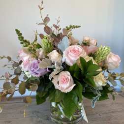 Pastel roses and greenery arranged in a clear glass vase