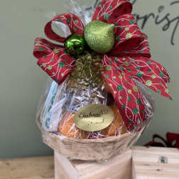 Gift basket wrapped in clear cellophane with a red holiday bow