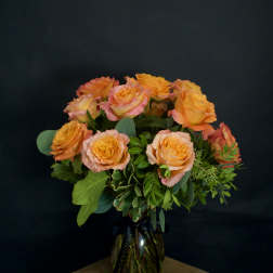 Orange and pink roses arranged in a glass vase