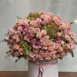 Large pink rose and hydrangea arrangement in a round box with ribbon