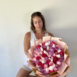 Woman holding a large bouquet of pink, red, white, and lavender roses