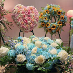 Large floral display with white roses and blue hydrangeas in front of wreaths