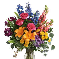 Colorful bouquet of roses, lilies, and snapdragons in a glass vase