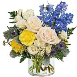 Bouquet of white roses, blue delphinium, and yellow carnations in a glass vase
