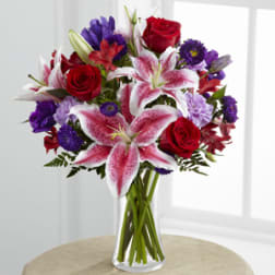 Bouquet of red roses and pink lilies in a clear glass vase