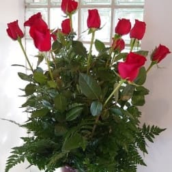 Tall bouquet of red roses in a burgundy vase