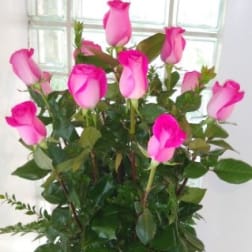 Pink roses arranged in a clear glass vase with greenery