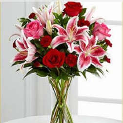 Bouquet of red roses and pink lilies in a clear glass vase