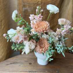 Peach and white floral arrangement in a white vase