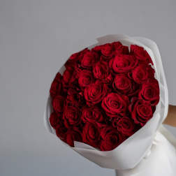 Large bouquet of tightly packed red roses wrapped in white paper.