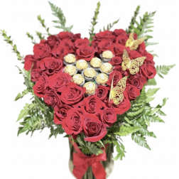 Heart-shaped bouquet of red roses with chocolates and butterfly accents in a vase