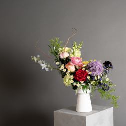 Mixed bouquet in a white vase with roses and purple blooms