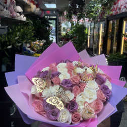 Bouquet of pink, white, and lavender roses wrapped in bright paper