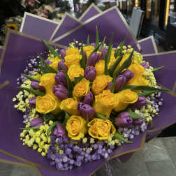 Bouquet of yellow roses and purple tulips wrapped in purple paper