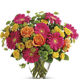 Bouquet of pink gerbera daisies and orange-yellow roses in a clear glass vase