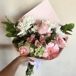 Pink and white bouquet with roses, daisies, and hydrangeas wrapped in pastel paper