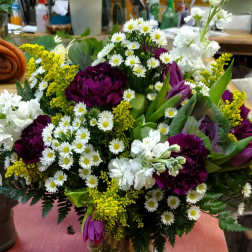 Mixed bouquet of purple, white, and yellow flowers in a glass vase