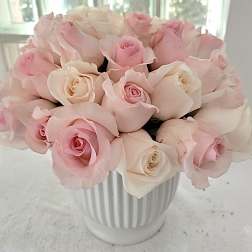 Pink and white roses arranged in a white ribbed vase