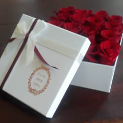 White gift box filled with red roses and tied with a ribbon