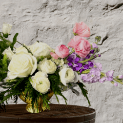 Pink and white roses with purple flowers in a gold vase