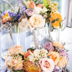 Pastel floral arrangements in clear glass vases with roses and mixed blooms