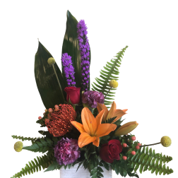 Tropical floral arrangement with orange lily, red roses, and purple blooms in a white box