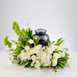 White floral arrangement with roses and tulips around a dark urn