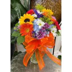 Colorful mixed bouquet in a glass vase with an orange ribbon