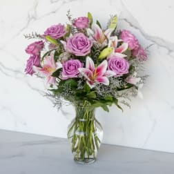 Pink roses and white lilies arranged in a clear glass vase
