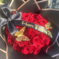 Bouquet of red roses wrapped in black paper with a birthday ribbon