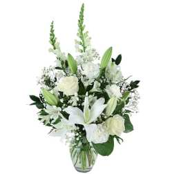 Tall white arrangement with lilies, roses, carnations, and snapdragons in a clear glass vase