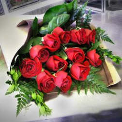 Bouquet of red roses with greenery wrapped in paper